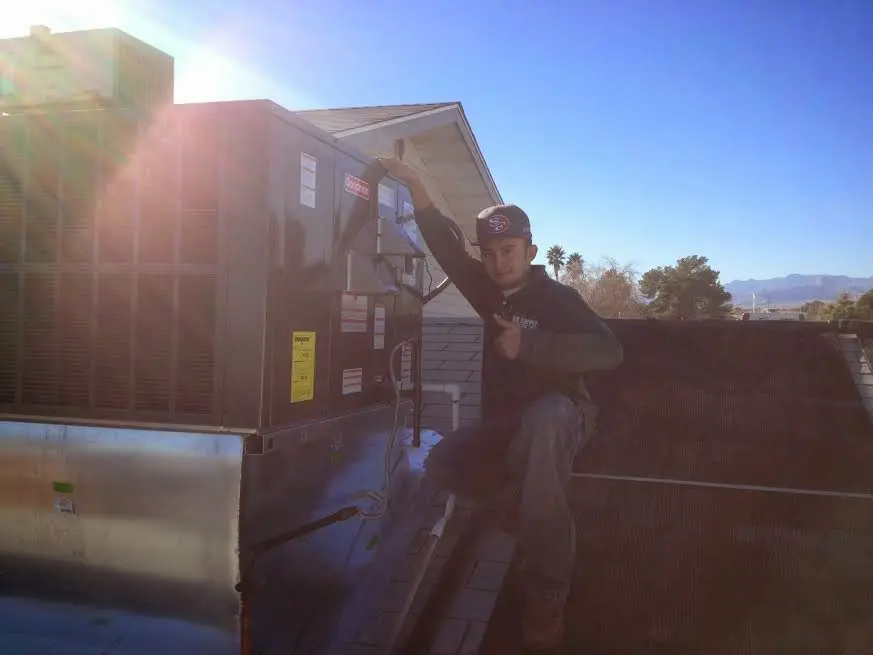 HVAC technician performing AC Tune-Up on a rooftop unit in Clute